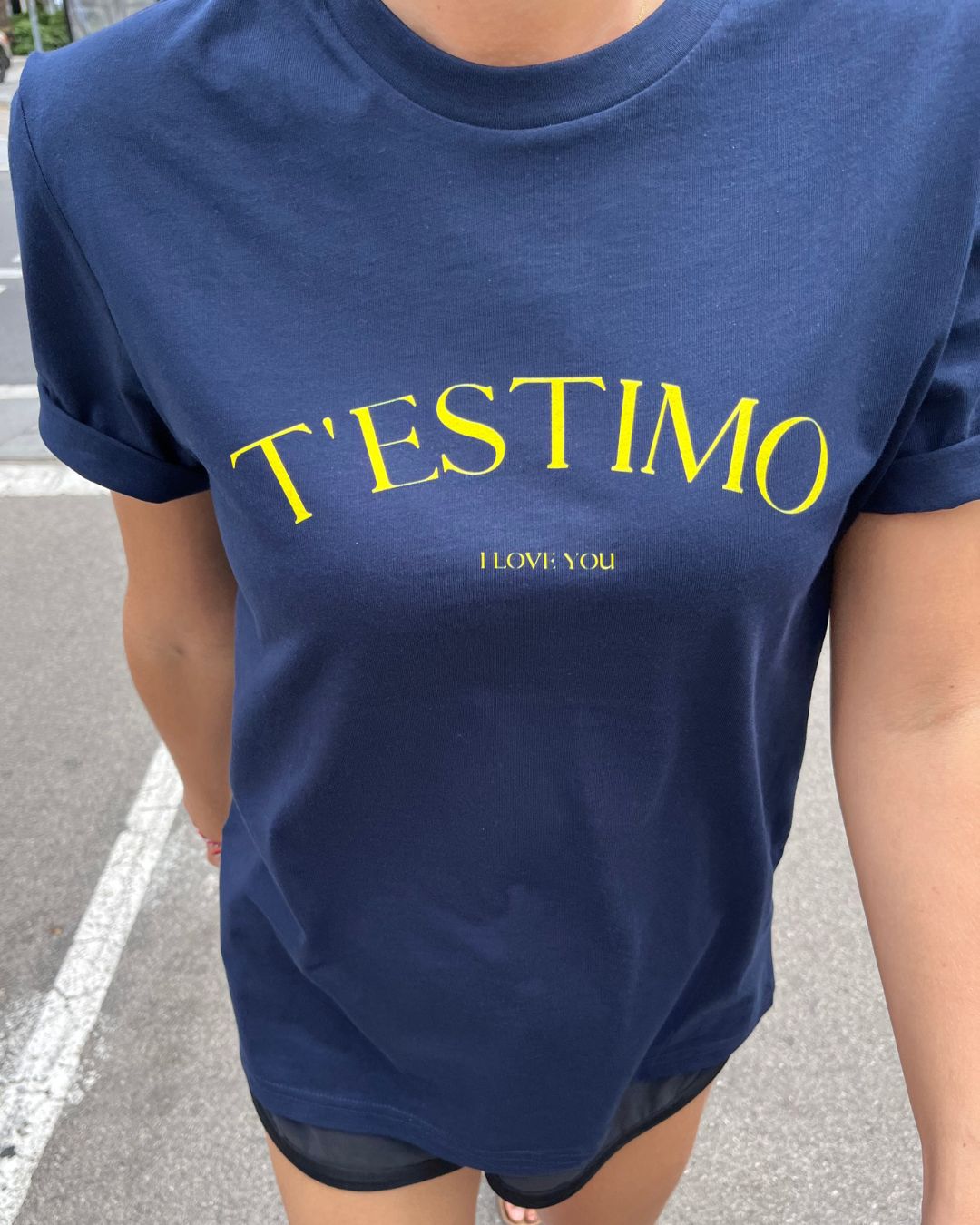 Samarreta blava amb el text "T'ESTIMO" en groc, disseny minimalista de Catalan Words.
